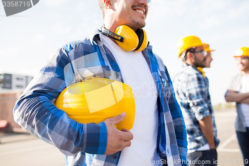 Image of close up of builder holding hardhat at building