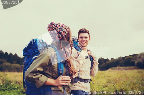 Image of smiling couple with backpacks hiking