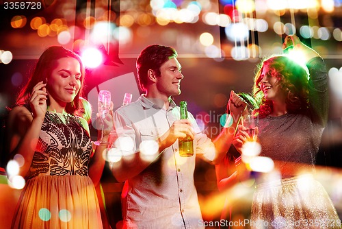 Image of smiling friends with wine glasses and beer in club