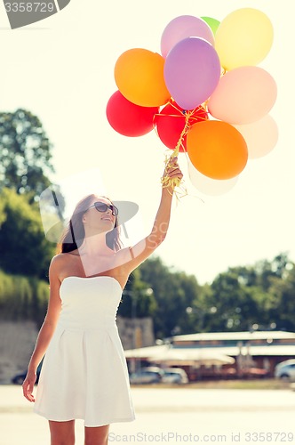 Image of smiling young woman in sunglasses with balloons