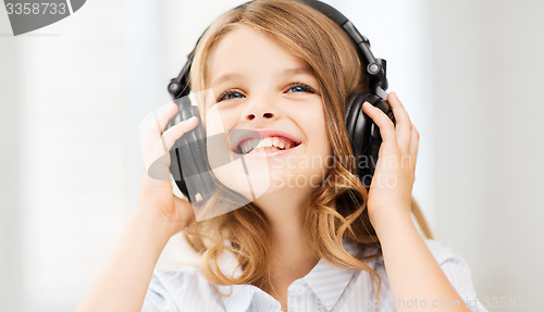 Image of smiling little girl with headphones at home