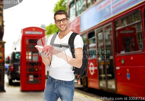 Image of happy young man with backpack and book travelling