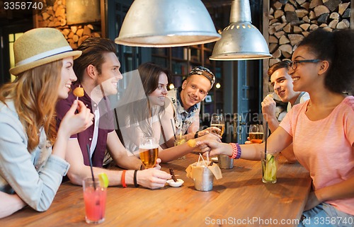Image of happy friends with drinks talking at bar or pub