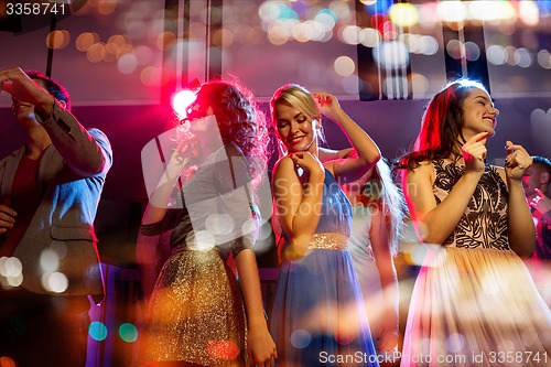 Image of happy friends dancing in club with holidays lights