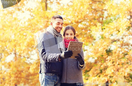 Image of smiling couple with tablet pc in autumn park