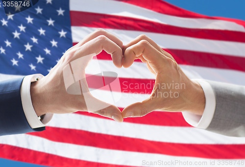 Image of close up of male gay couple hands showing heart