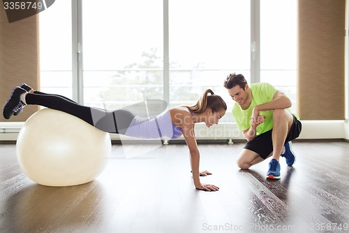 Image of smiling man and woman with exercise ball in gym