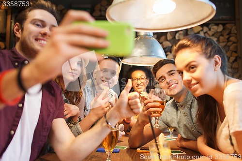 Image of happy friends with smartphone taking selfie at bar