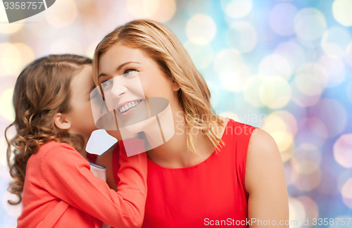 Image of happy mother and girl whispering into ear