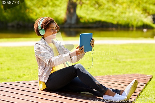 Image of happy african woman with tablet pc and headphones