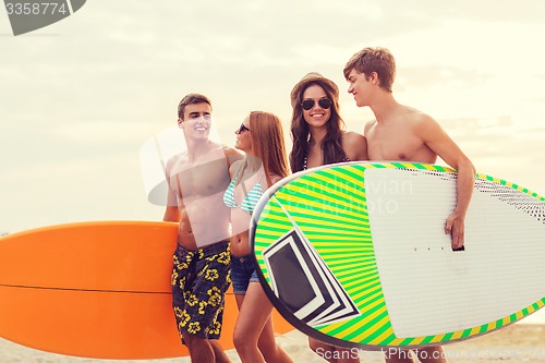 Image of smiling friends in sunglasses with surfs on beach