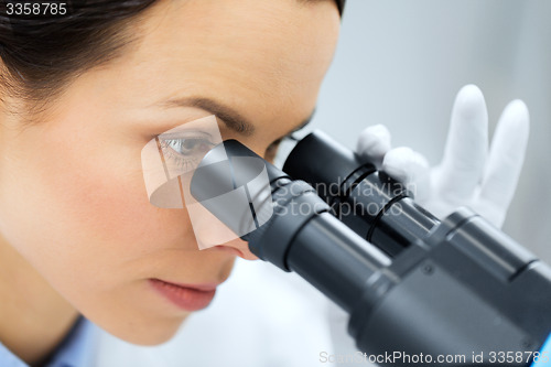 Image of close up of scientist looking to microscope in lab