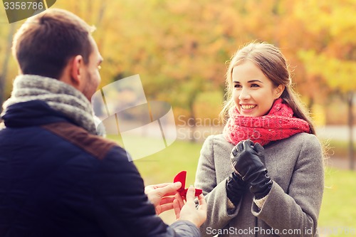 Image of smiling couple with engagement ring in gift box