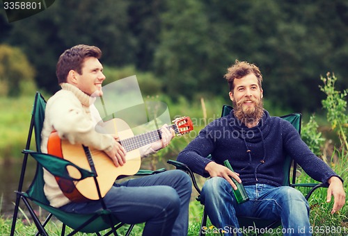 Image of smiling tourists playing guitar in camping