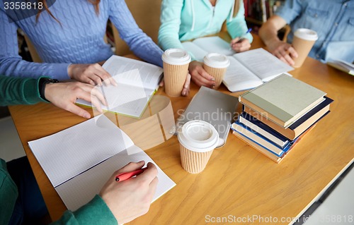 Image of close up of hands with books writing to notebooks