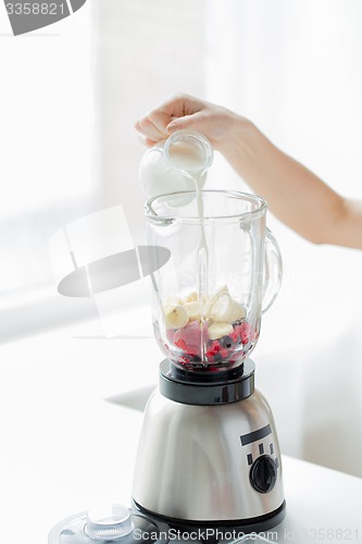 Image of close up of woman hand pouring milk to blender