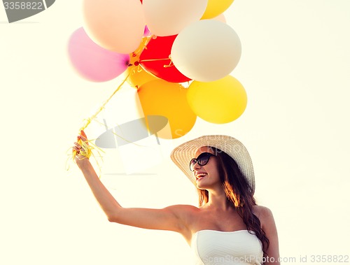 Image of smiling young woman in sunglasses with balloons