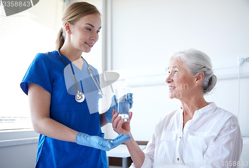 Image of nurse giving medicine to senior woman at hospital