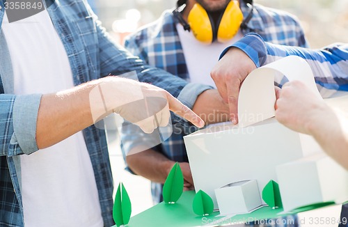 Image of close up of builders with paper house model