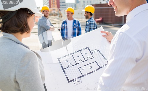 Image of close up of architects with blueprint at building