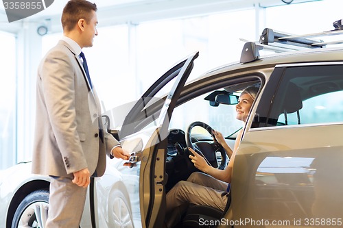 Image of happy woman with car dealer in auto show or salon