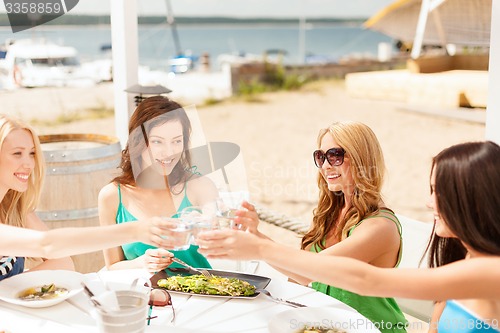 Image of smiling girls looking at tablet pc in cafe