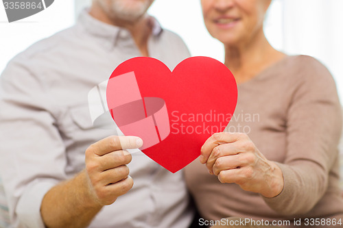 Image of close up of happy senior couple holding red heart