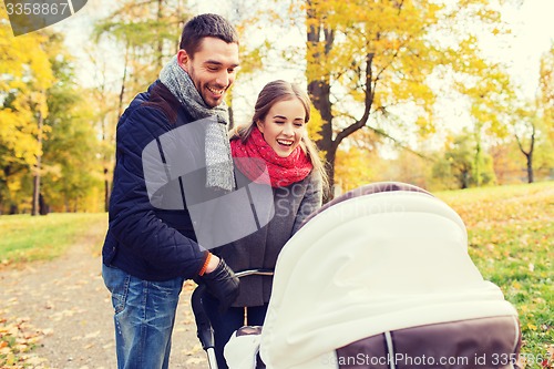 Image of smiling couple with baby pram in autumn park