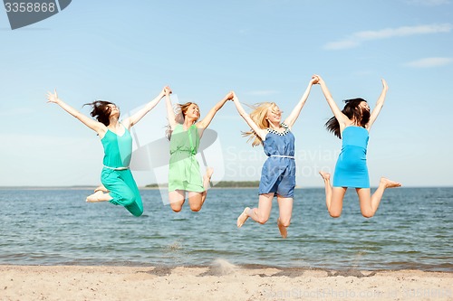 Image of smiling girls jumping on the beach