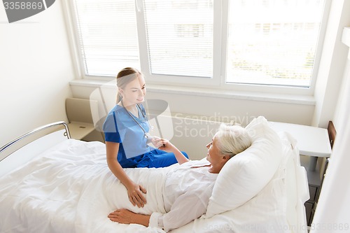 Image of doctor or nurse visiting senior woman at hospital