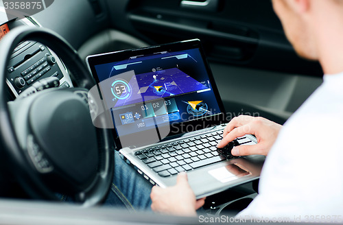 Image of man using navigation on laptop computer in car