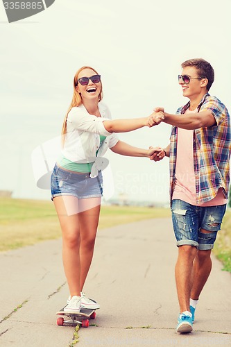 Image of smiling couple with skateboard outdoors