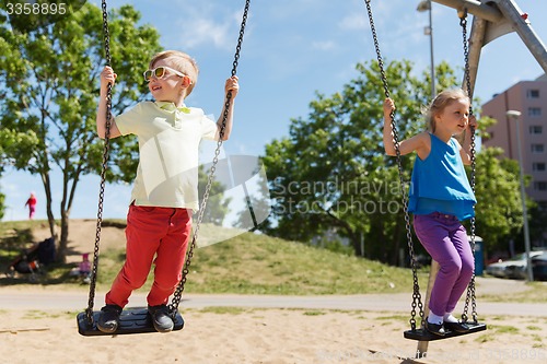 Image of two happy kids swinging on swing at playground