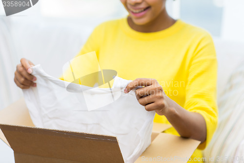 Image of happy african young woman with parcel box at home