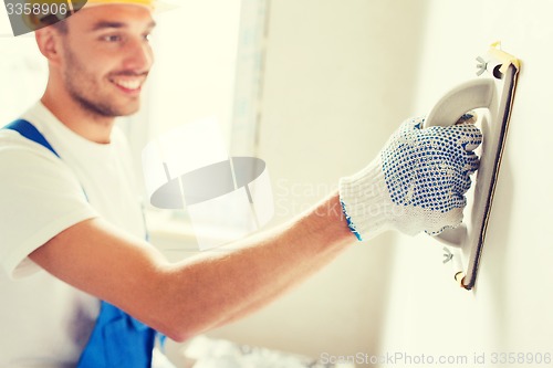 Image of smiling builder with grinding tool indoors