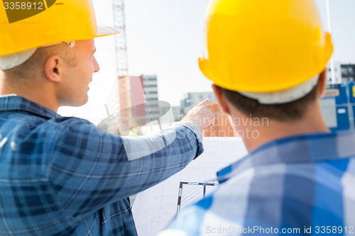 Image of close up of builders with blueprint at building