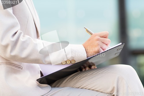 Image of close up of business woman writing to clipboard