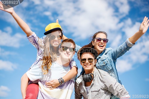 Image of smiling teenagers in sunglasses having fun outside