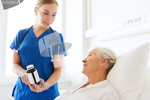 Image of nurse giving medicine to senior woman at hospital