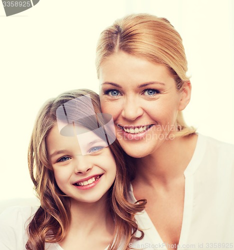 Image of smiling mother and little girl at home