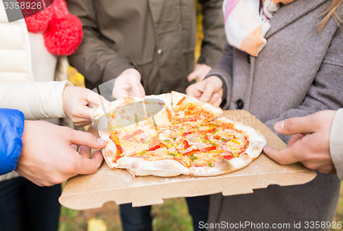 Image of close up of friends hands eating pizza outdoors