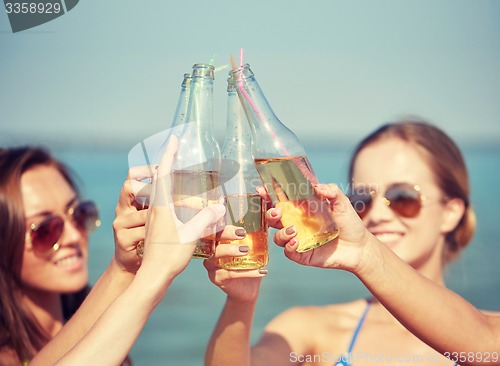 Image of close up of happy young women with drinks on beach