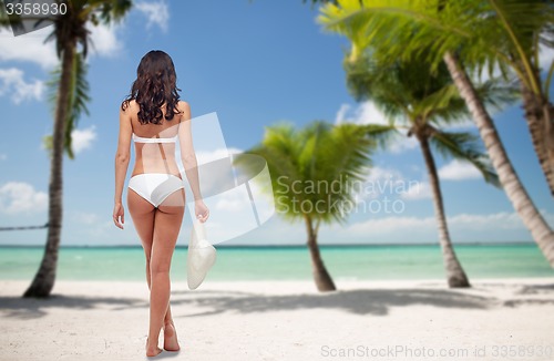 Image of woman in white bikini swimsuit on tropical beach