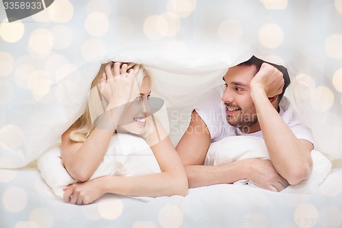 Image of happy couple lying in bed and talking at home