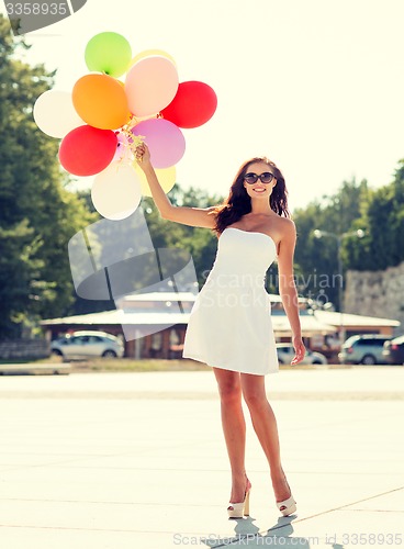 Image of smiling young woman in sunglasses with balloons