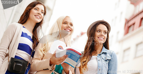 Image of three beautiful girls with tourist book in city