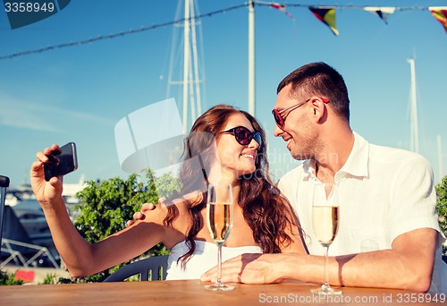 Image of smiling couple drinking champagne at cafe