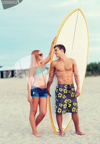 Image of smiling couple in sunglasses with surfs on beach