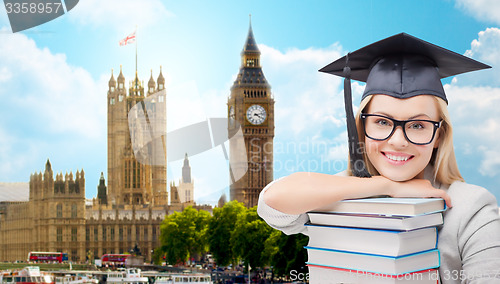 Image of student in trencher cap with books over london
