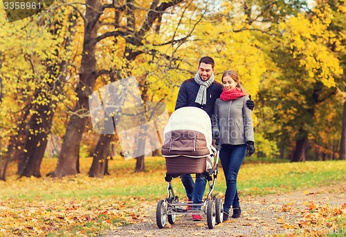 Image of smiling couple with baby pram in autumn park